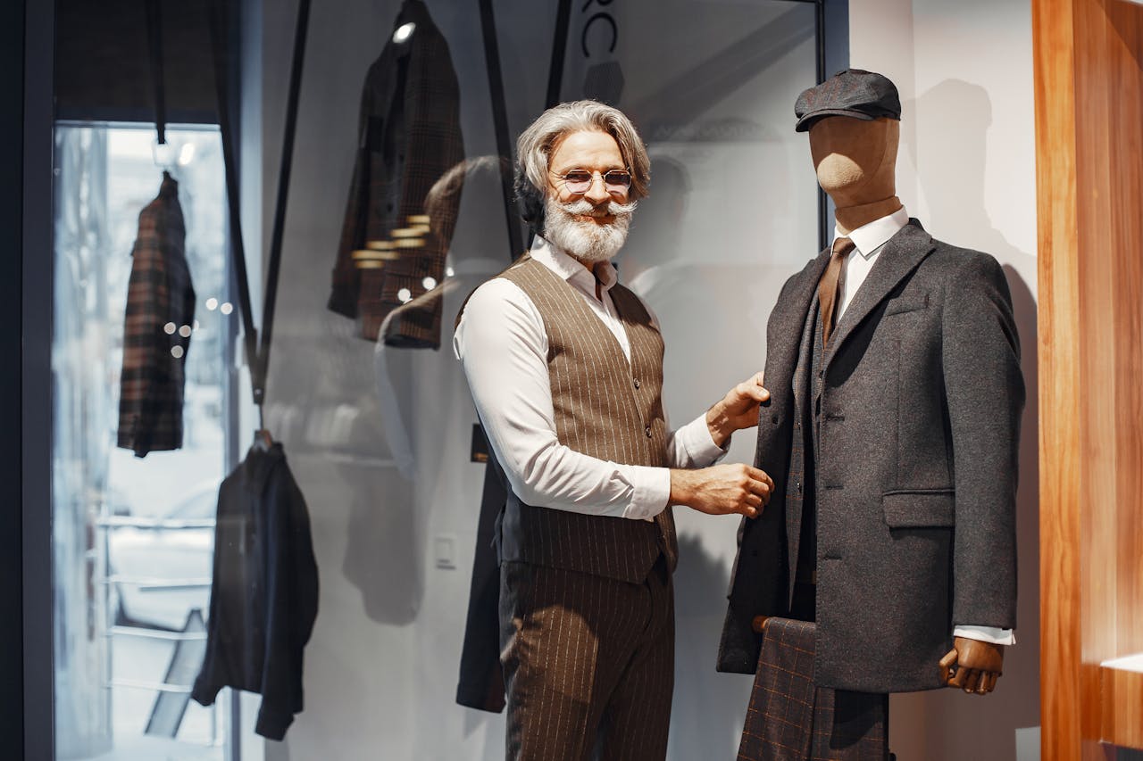 Mastering the First Impression: Your intriguing post title goes here Elegant senior man in tailored vest styling a mannequin in designer menswear inside a fashion boutique.